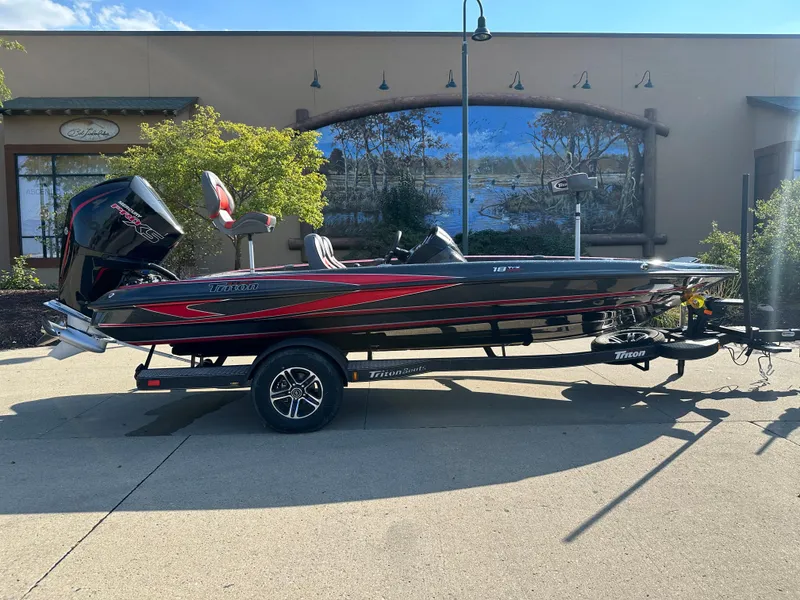 Slide: The Image of 2024 Triton 18 TrX bass boat with trailer, parked outdoors. - 0