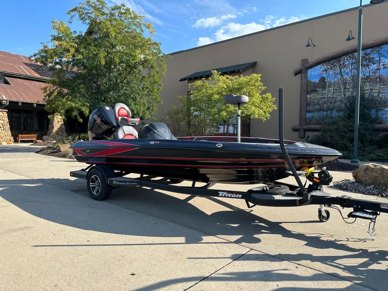 Slide: The Image of 2024 Triton 18 TrX bass boat on trailer, parked outdoors. - 2