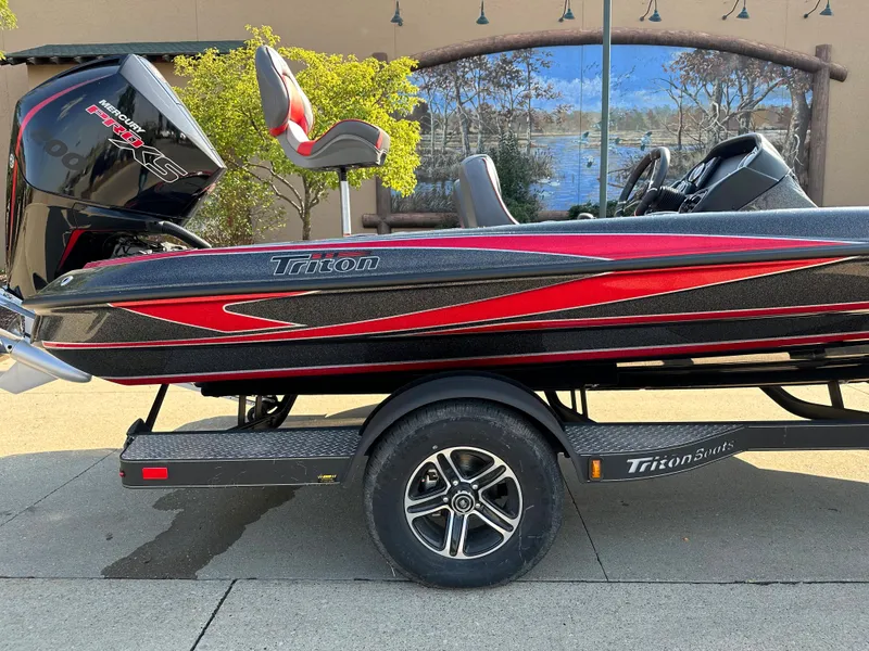 Slide: The Image of 2024 Triton 18 TrX bass boat with red and black design on trailer. - 3