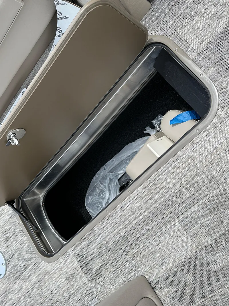 Slide: The Image of 2024 Ranger Reata 223C storage compartment with gray flooring and beige interior. - 11