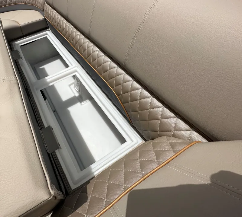 Slide: The Image of 2024 Ranger Reata 223C boat with open storage compartment in beige quilted seats. - 13