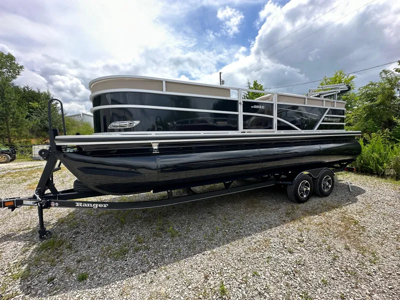 Slide: The Image of 2024 Ranger Reata 223C pontoon boat on a trailer, parked outdoors. - 2