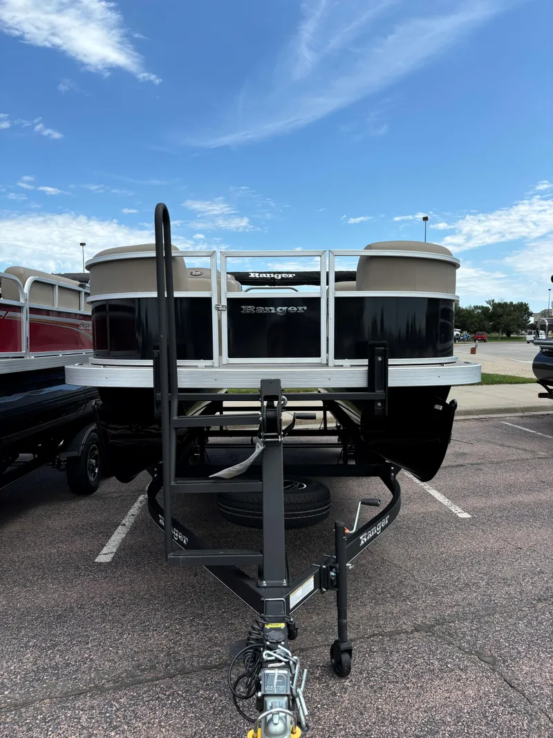 Slide: The Image of 2024 Ranger Reata 200C pontoon boat on a trailer in a parking lot. - 2