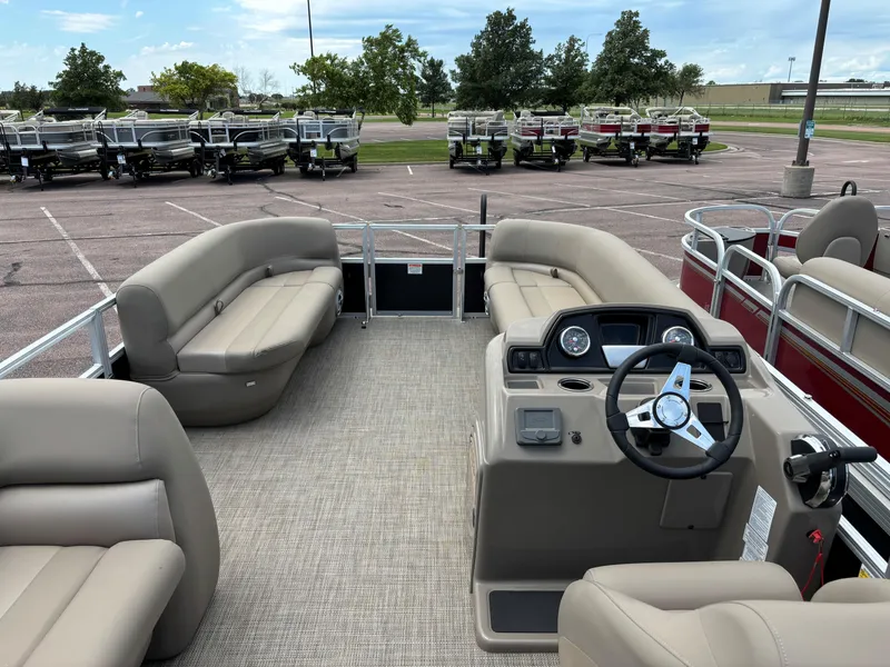 Slide: The Image of 2024 Ranger Reata 200C pontoon boat interior with beige seating and steering console. - 6