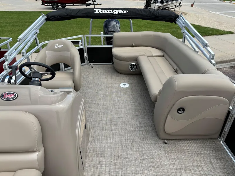 Slide: The Image of 2024 Ranger Reata 200C pontoon boat interior with beige seating and steering console. - 8