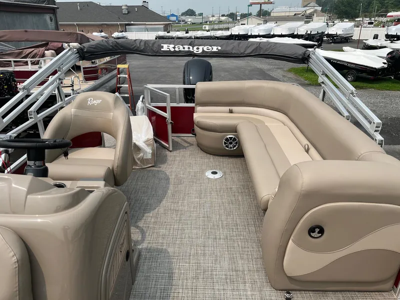 Slide: The Image of 2024 Ranger Reata 200C pontoon boat with beige seating and steering console. - 11