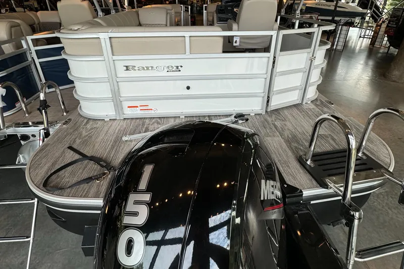 Slide: The Image of 2024 Ranger Reata 223C pontoon boat with 150 HP Mercury engine, docked indoors. - 3