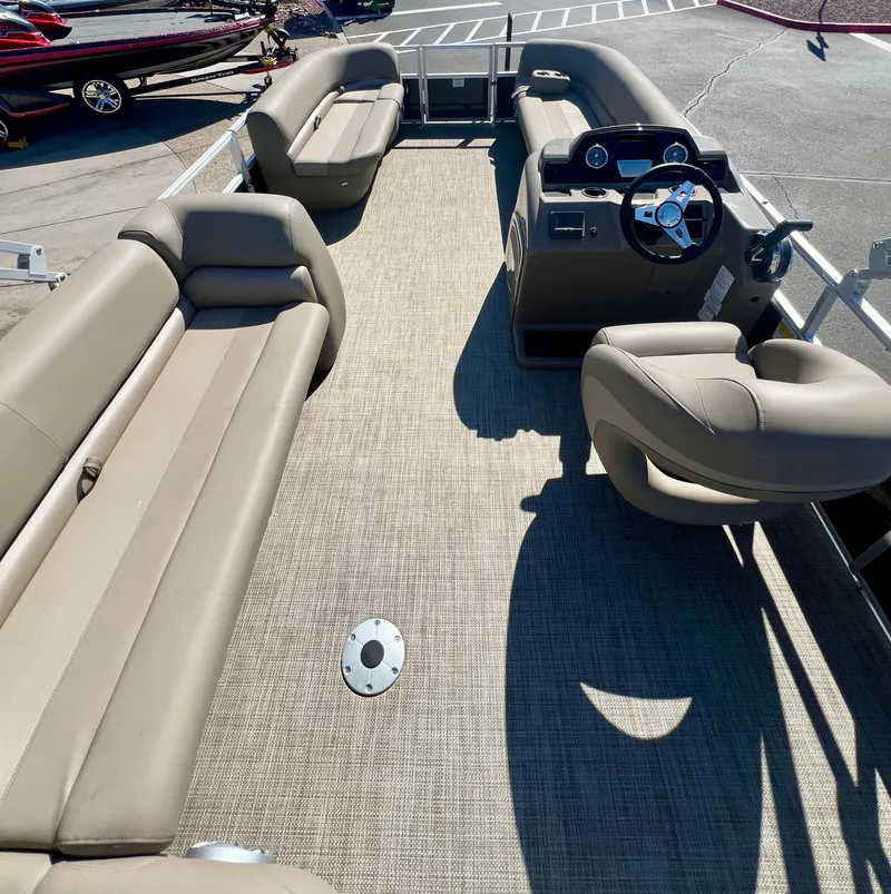 Slide: The Image of 2024 Ranger Reata 200C pontoon boat interior with beige seating and steering console. - 3