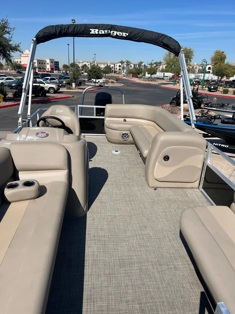 Slide: The Image of 2024 Ranger Reata 200C pontoon boat with beige seating and canopy. - 4