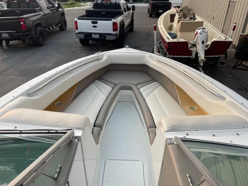 Slide: The Image of 1998 Cobalt 252 boat with spacious bow seating, parked near trucks and another boat. - 12