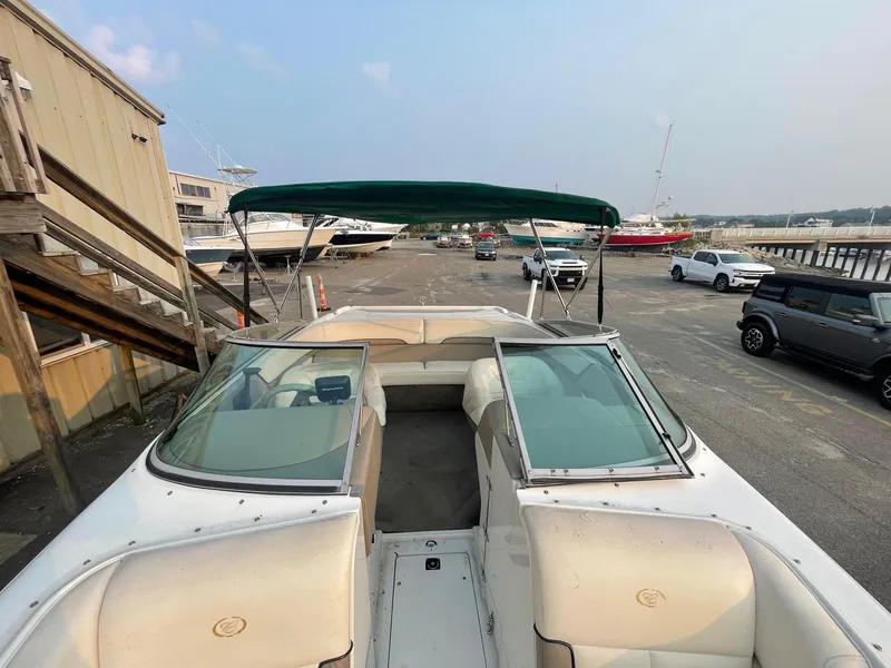 Slide: The Image of 1998 Cobalt 252 boat with green canopy in a marina parking lot. - 16