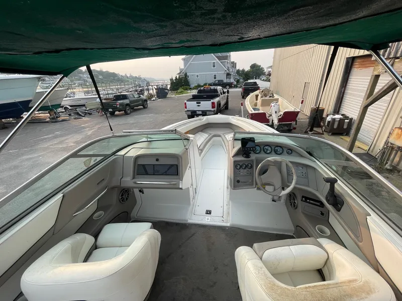 Slide: The Image of 1998 Cobalt 252 boat interior with white seats and dashboard, docked at a marina. - 24