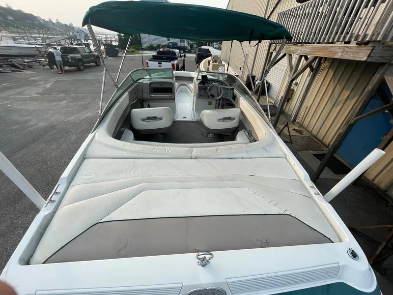 Slide: The Image of 1998 Cobalt 252 boat with green canopy and white interior, docked near a marina. - 28