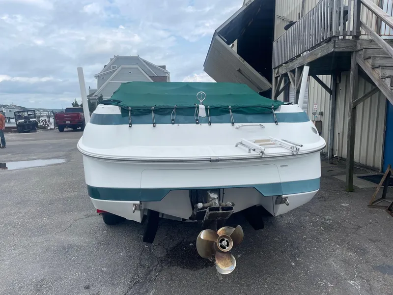 Slide: The Image of 1998 Cobalt 252 boat with green cover, docked near a building. - 7