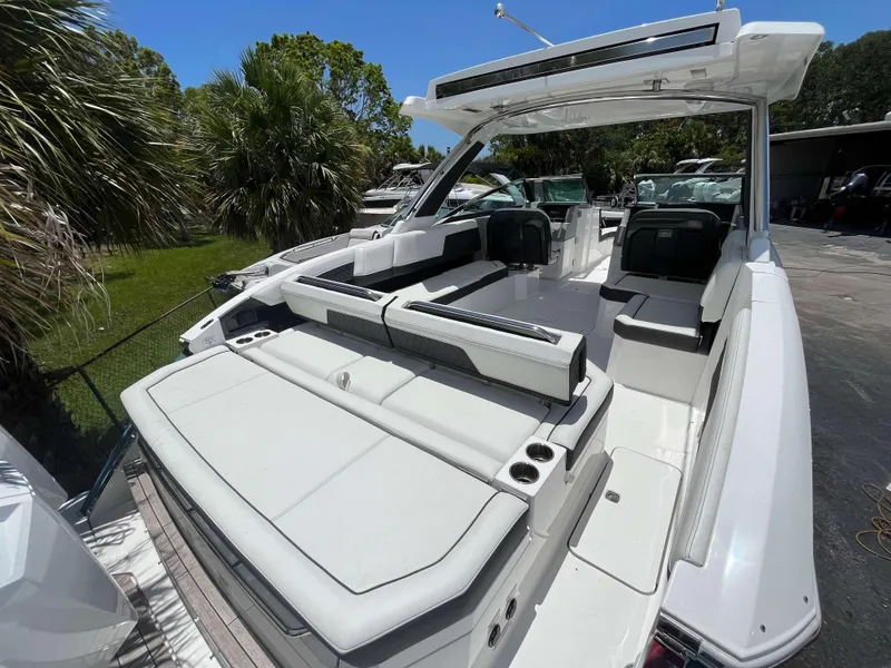 Slide: The Image of 2023 Cobalt R33 boat with spacious seating and sleek design, surrounded by lush greenery. - 1