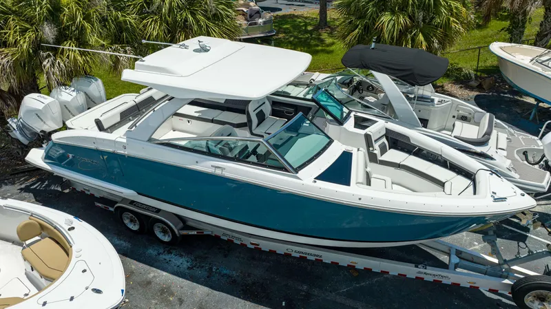 Slide: The Image of 2023 Cobalt R33 boat on trailer, surrounded by palm trees and other boats. - 16