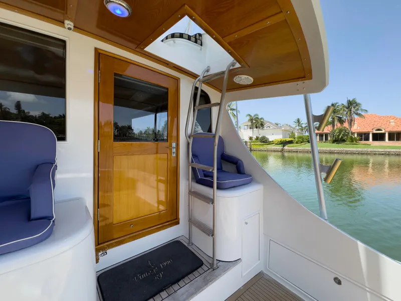 Slide: The Image of 1990 Buddy Davis 61 Convertible yacht with wooden door and seating area by the water. - 32