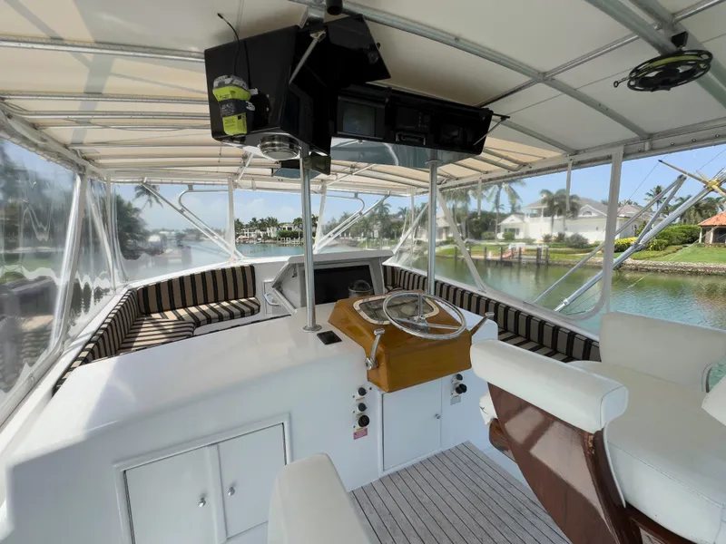 Slide: The Image of 1990 Buddy Davis 61 Convertible yacht helm with striped seating and waterfront view. - 37