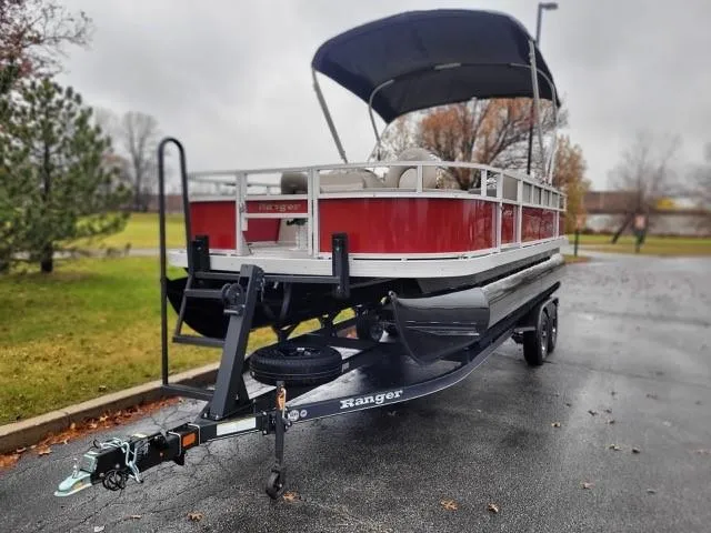Slide: The Image of 2024 Ranger Reata 200F pontoon boat on trailer, parked outdoors. - 1
