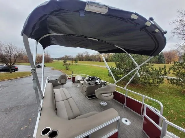 Slide: The Image of 2024 Ranger Reata 200F pontoon boat with canopy, spacious seating, and modern controls. - 4