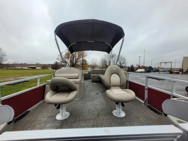 Slide: The Image of 2024 Ranger Reata 200F pontoon boat with canopy and seating, parked outdoors. - 5