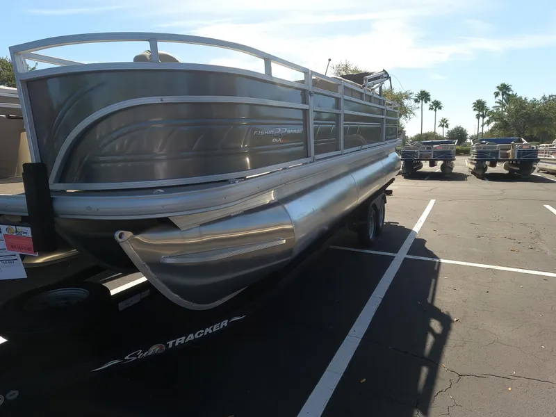 The Image of 2024 Sun Tracker Fishin' Barge 22 XP3 pontoon boat in a parking lot. - 0