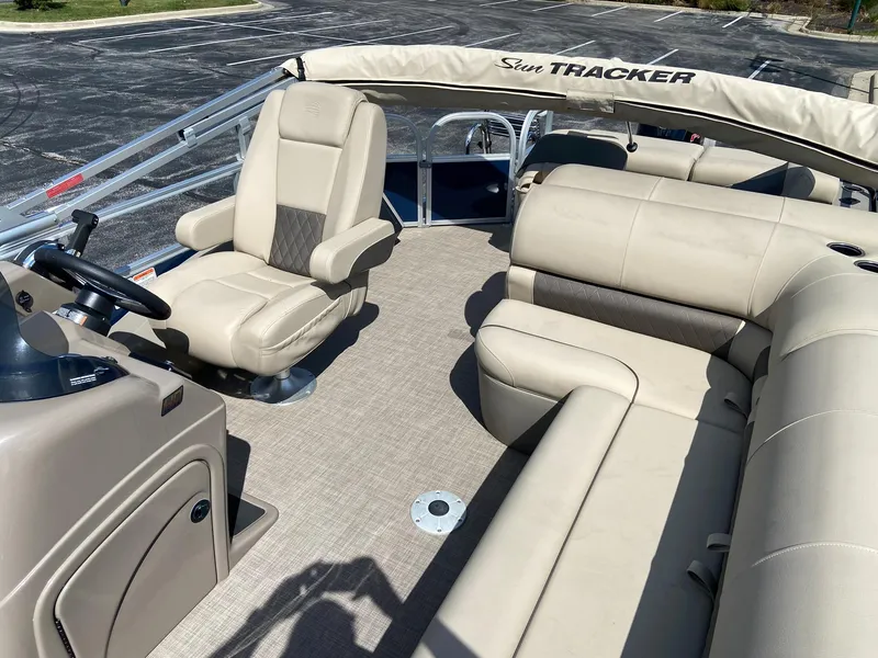 Slide: The Image of 2023 Sun Tracker Fishin' Barge 22 DLX interior with beige seating and steering console. - 4