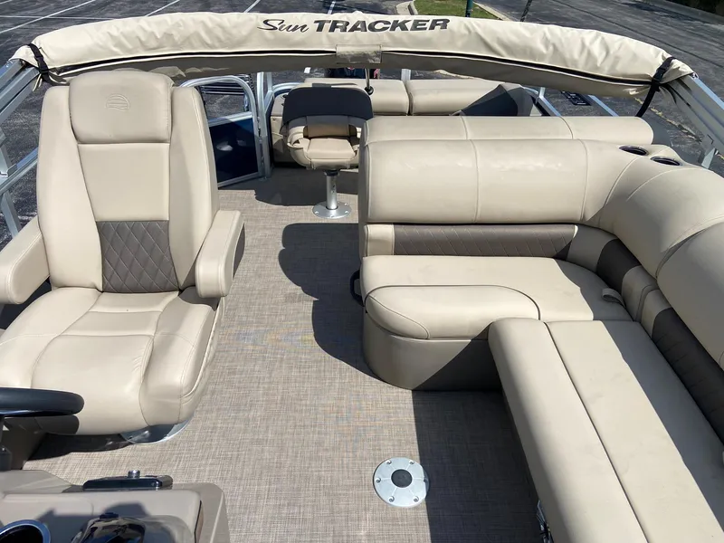 Slide: The Image of 2023 Sun Tracker Fishin' Barge 22 DLX interior with beige seating and canopy. - 7