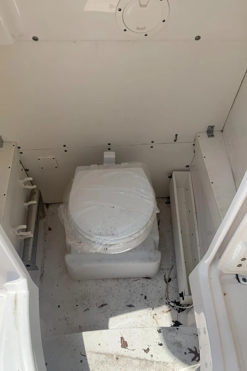 Slide: The Image of 2022 Robalo R230 boat interior with toilet, white and clean design. - 30