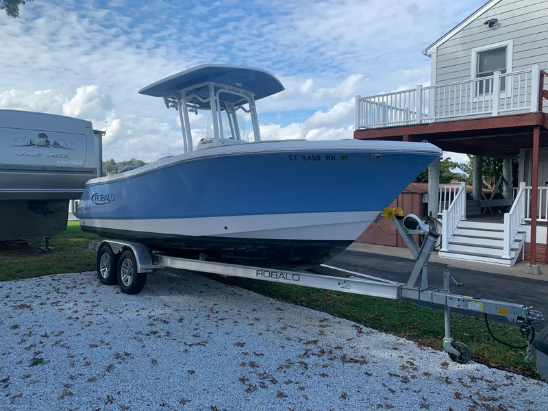 Slide: The Image of 2022 Robalo R230 boat on a trailer in a residential driveway. - 34