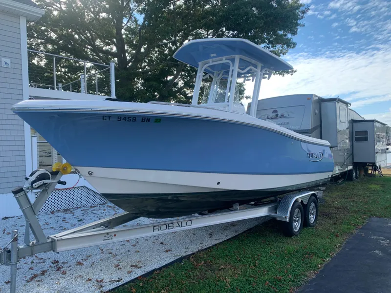 Slide: The Image of 2022 Robalo R230 boat on trailer, parked outdoors near a house and RV. - 38