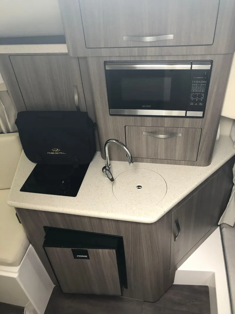 Slide: The Image of Compact kitchen area in a 2019 Regal 28 Express boat with microwave and sink. - 35