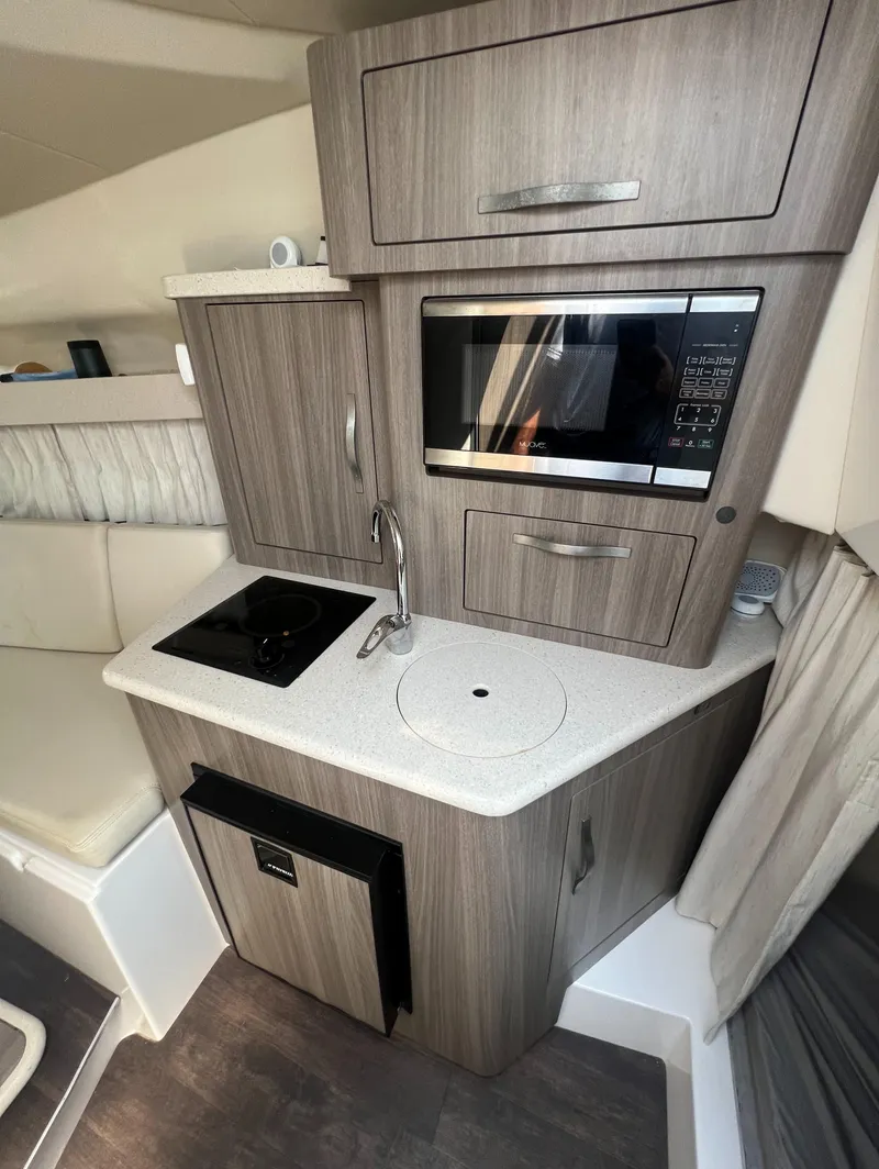Slide: The Image of 2019 Regal 28 Express boat interior kitchen with microwave, sink, and stove. - 37