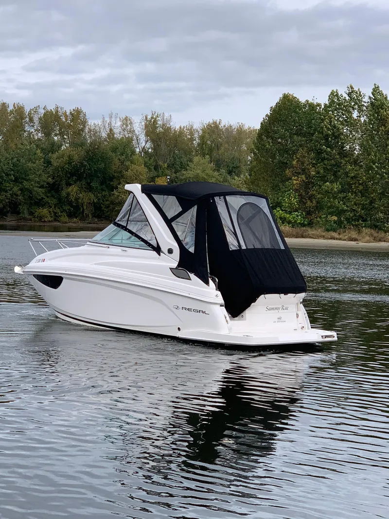 Slide: The Image of 2019 Regal 28 Express boat on a calm lake with trees in the background. - 4