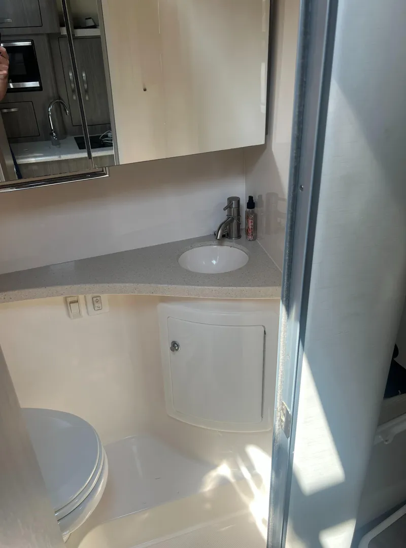 Slide: The Image of 2019 Regal 28 Express boat bathroom with sink, mirror, and storage cabinet. - 43