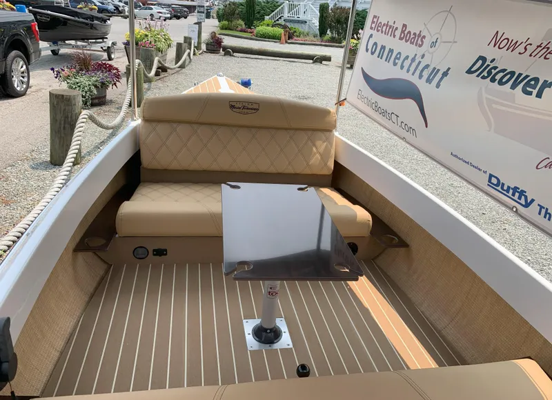 Slide: The Image of 2023 Vision Marine Technologies Quietude 156 electric boat interior with tan seating and table. - 1