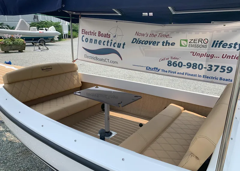 Slide: The Image of 2023 Vision Marine Technologies Quietude 156 electric boat interior with tan seating and promotional banner. - 2
