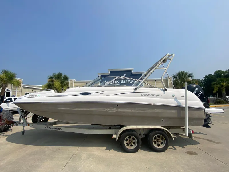 Slide: The Image of 2009 Starcraft 2410 OB Limited boat on a trailer in a marina. - 0