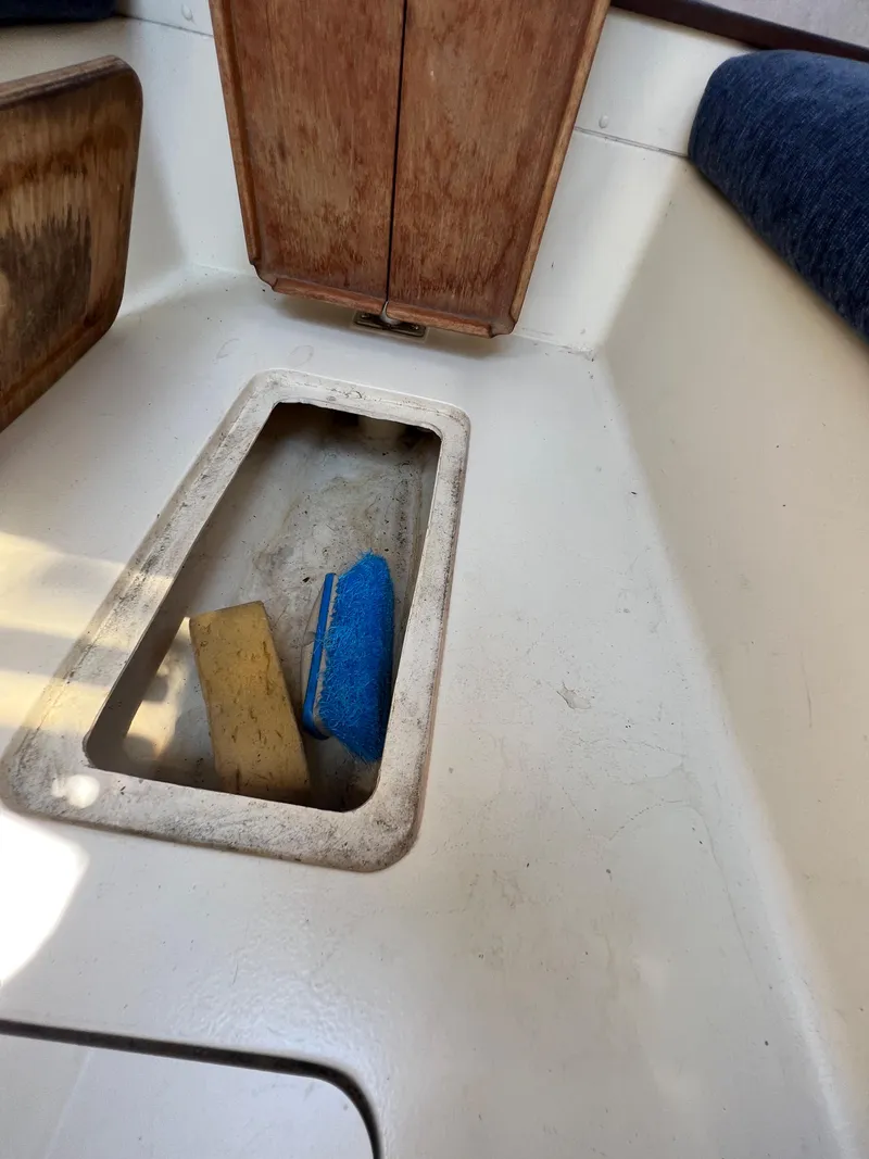 Slide: The Image of Interior of 2007 Hunter 25 sailboat with storage compartment and cleaning supplies. - 32