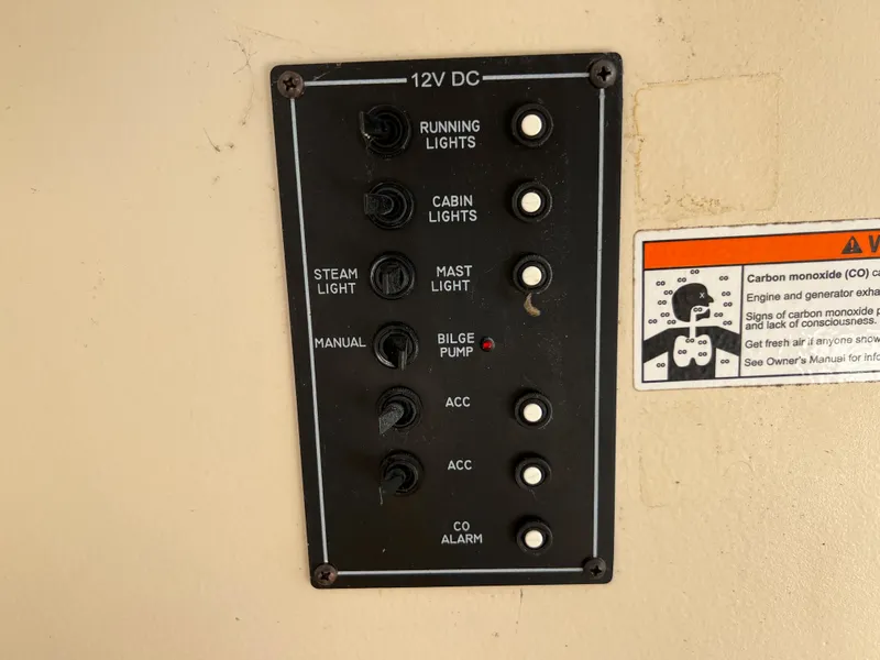Slide: The Image of Control panel of a 2007 Hunter 25 boat with various switches and warning label. - 35