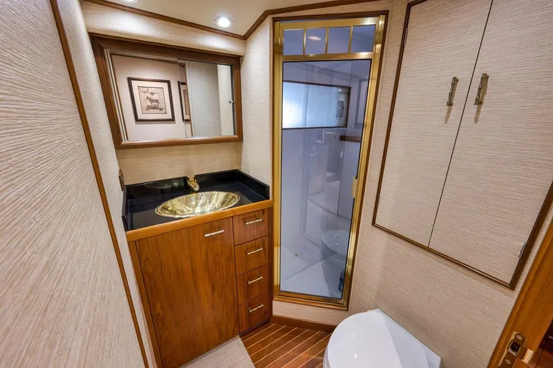 Slide: The Image of Luxurious bathroom interior of a 2001 Rybovich Sportfisherman yacht with gold sink and wood accents. - 12
