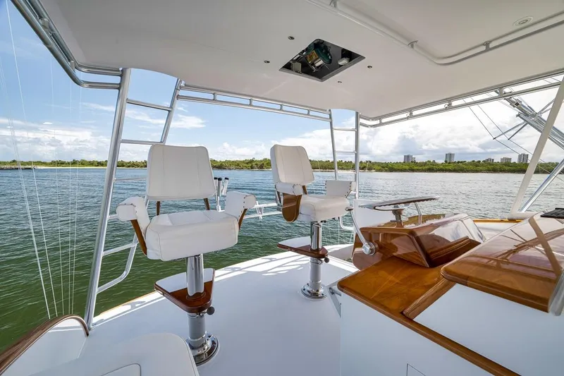Slide: The Image of 2001 Rybovich Sportfisherman yacht helm with white captain chairs, overlooking serene waters. - 22