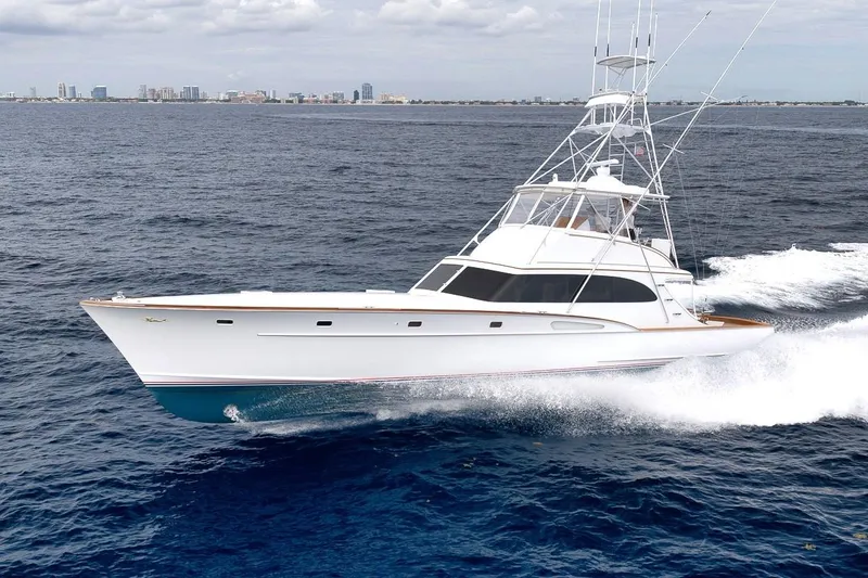 Slide: The Image of 2001 Rybovich Sportfisherman yacht cruising on open ocean with city skyline in background. - 48