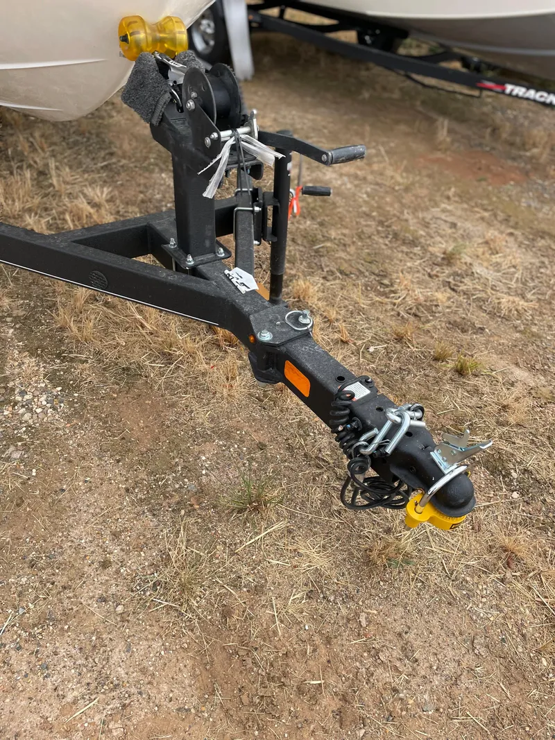 Slide: The Image of Trailer hitch of a 2024 Tahoe T18 boat on dry grass. - 8
