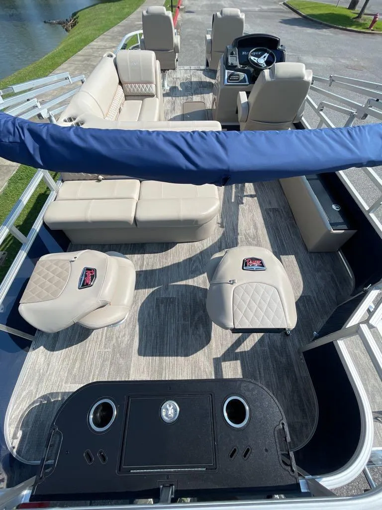 Slide: The Image of 2024 Ranger Reata 223F pontoon boat interior with beige seating and blue canopy. - 3