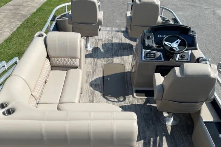 Slide: The Image of 2024 Ranger Reata 223F pontoon boat interior with beige seating and modern helm. - 7