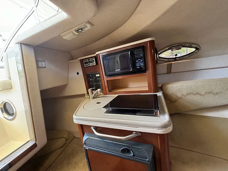 Slide: The Image of 2008 Sea Ray 240 Sundancer cabin kitchenette with microwave, sink, and stove. - 16