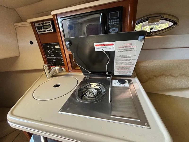 Slide: The Image of 2008 Sea Ray 240 Sundancer galley with stove, sink, and microwave. - 17
