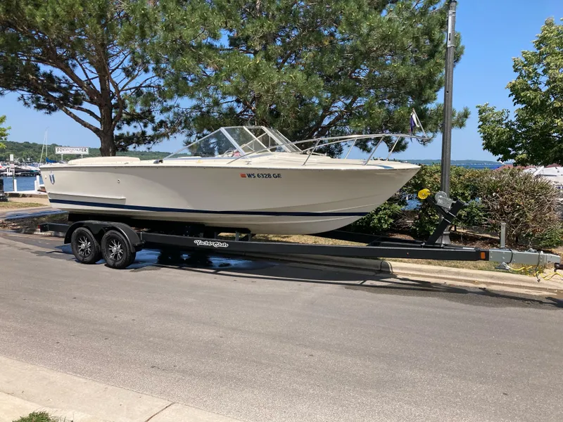 Slide: The Image of 1970 Chris-Craft Lancer 23 boat on a trailer, parked near a marina. - 13