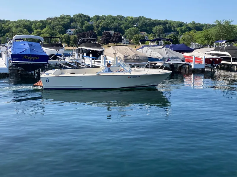 Slide: The Image of 1970 Chris-Craft Lancer 23 boat cruising near a marina with docked boats. - 4